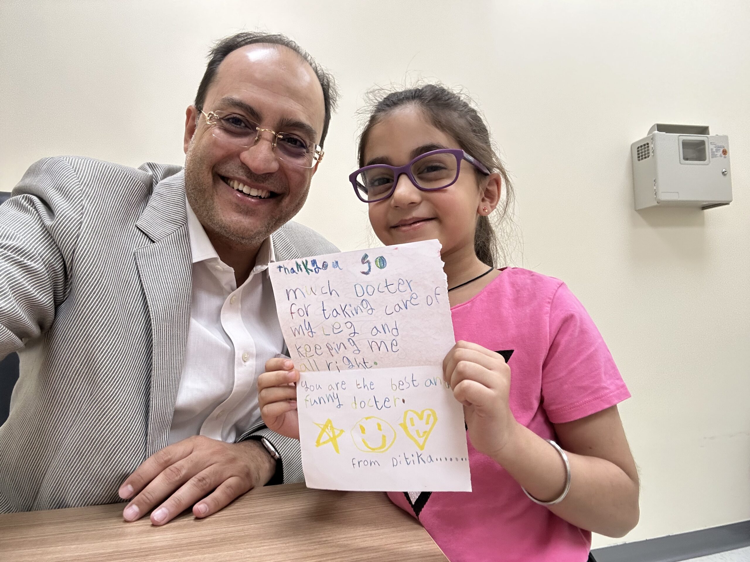 Dr. Mohamed Mashhour and a young girl joyfully show a note